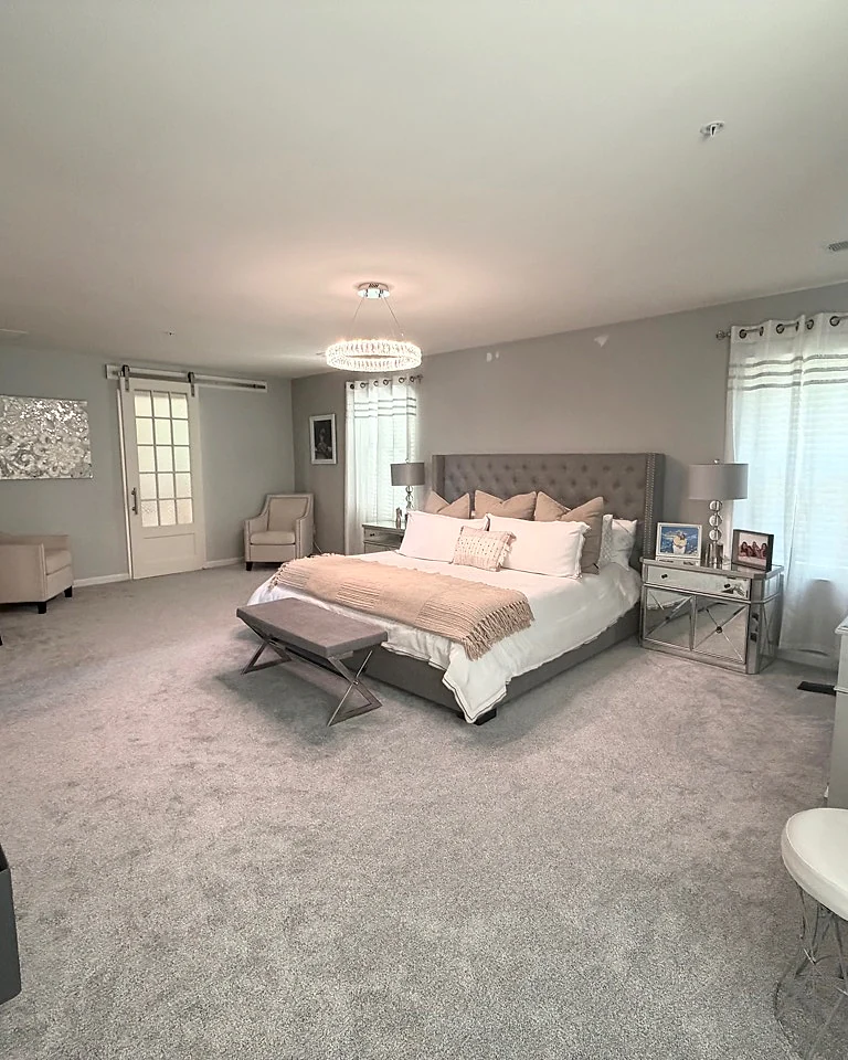 Finished spacious primary bedroom with freshly cleaned carpet and neatly arranged bedding