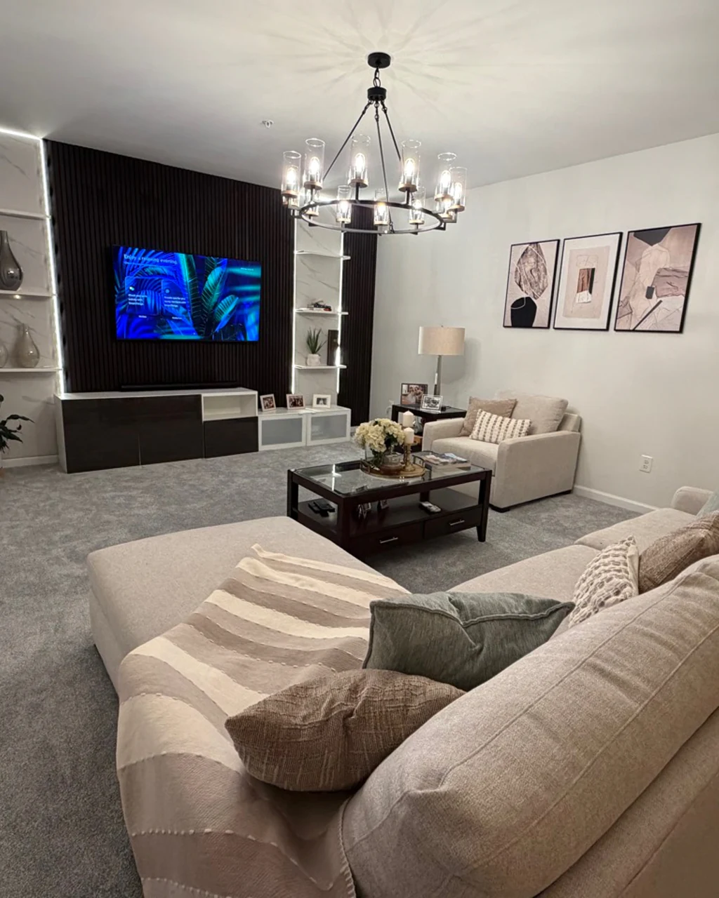 Finished living room with clean carpet, seating, and illuminated media wall